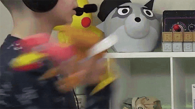 a child wearing headphones is playing with a toy in front of a shelf with toys on it