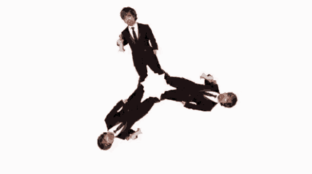 a man in a suit and tie is standing in a circle of three other men .