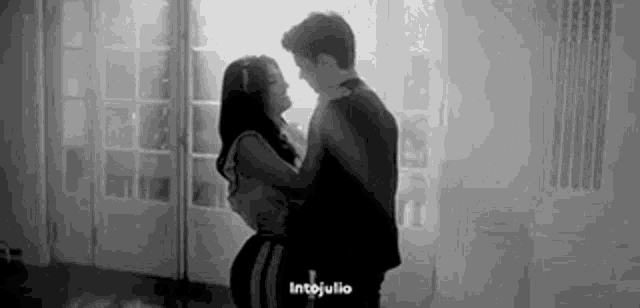 a man and a woman are dancing in a black and white photo .