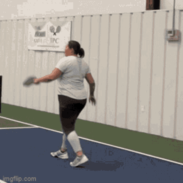 a woman on a tennis court with a sign that says tpc