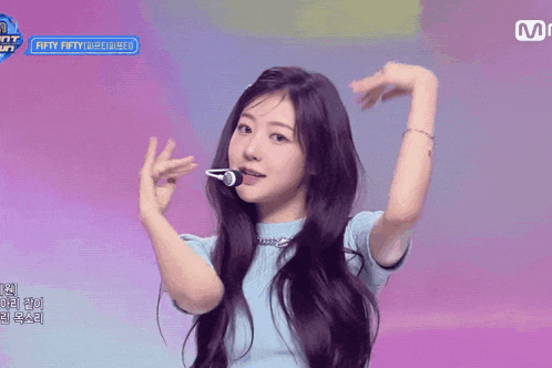 a girl with purple hair is dancing in front of a microphone with fifty fifty written on it