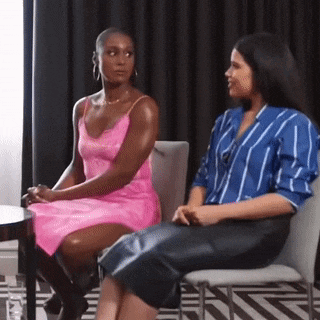 two women are sitting in chairs talking to each other .