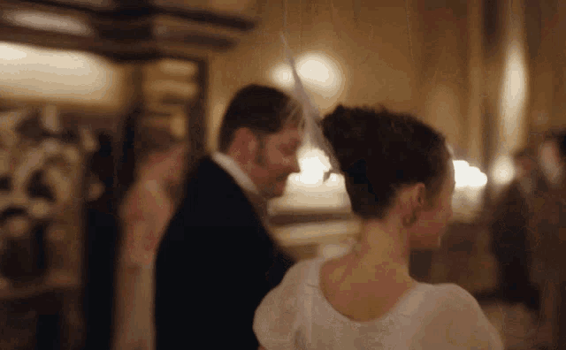 a woman in a white dress is dancing with a man in a suit