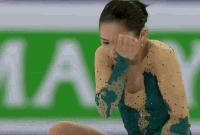 a female figure skater is sitting on the ice and crying .