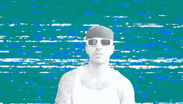 a man wearing sunglasses and a hat with the letter d on it is standing in front of a blue background