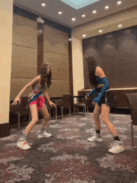two young girls are dancing in a room with a patterned carpet