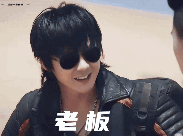 a man wearing sunglasses and a leather jacket has chinese writing on the bottom