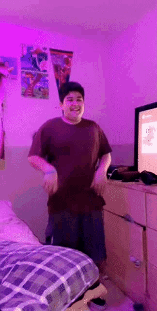 a boy is dancing in a bedroom with purple lights and a tv that says xbox on it