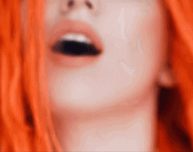 a close up of a woman 's face with red hair