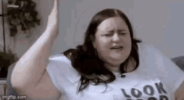 a woman is sitting on a couch making a funny face with her hands in the air .