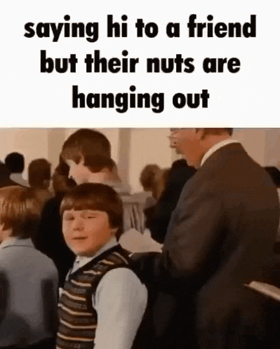 a man in a suit is standing next to a boy in a crowd of people and saying hi to a friend .