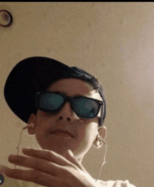 a young man wearing sunglasses and a hat takes a selfie
