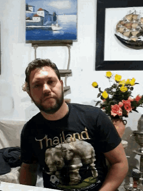 a man with a beard wears a black shirt that says thailand