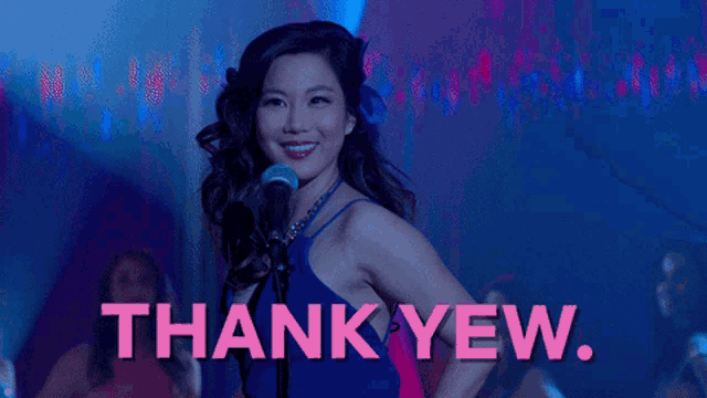 a woman in a blue dress singing into a microphone with the words thank yew behind her