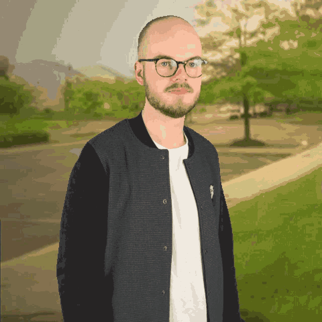 a bald man wearing glasses and a black jacket