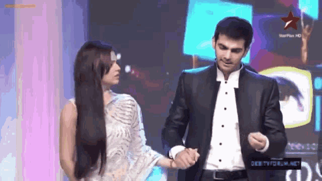 a man in a suit holds a woman 's hand in front of a star plus hd logo