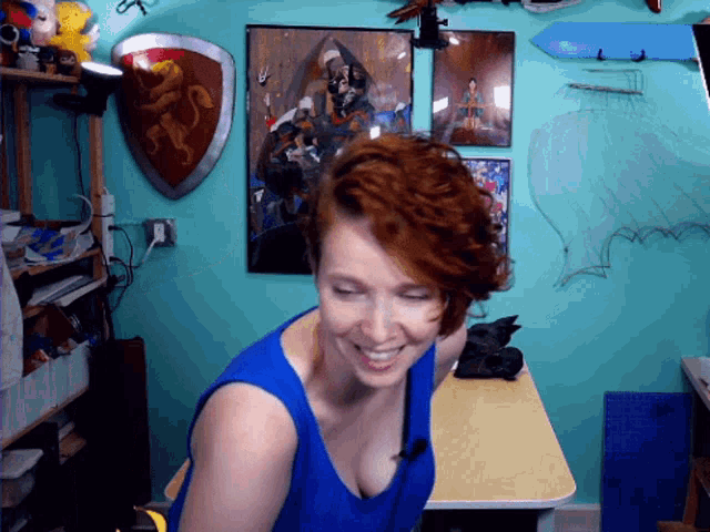 a woman in a blue tank top is smiling in front of a lion shield