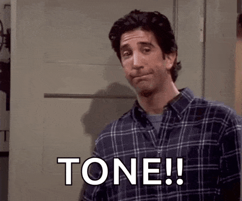 a man in a plaid shirt is making a funny face and says tone !