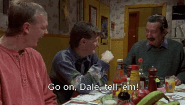 a group of men are sitting at a table and one of them is saying " go on dale tell em "
