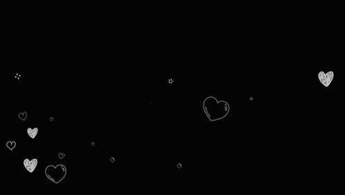 a bunch of white hearts are falling on a black background .