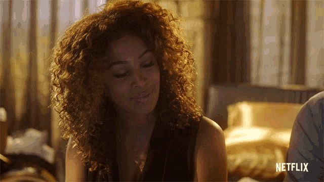 a woman with curly hair is sitting in front of a netflix sign