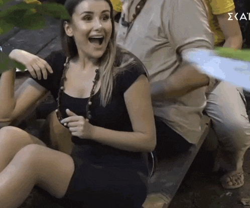 a woman in a black dress is sitting on the ground with her mouth wide open