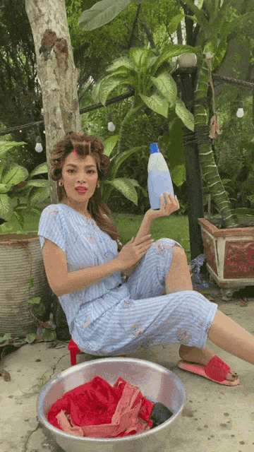 a woman is sitting on the ground holding a bottle of liquid