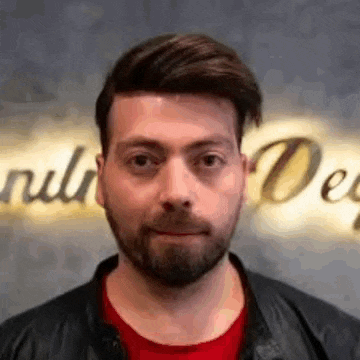 a man with a beard and a red shirt is making a funny face .