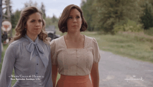 two women standing next to each other with a hallmark ad behind them