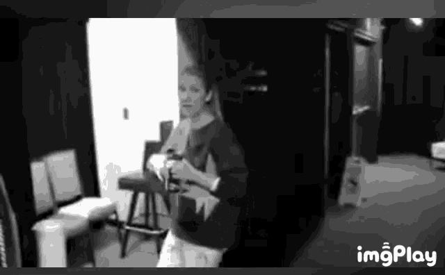 a black and white photo of a woman standing in a room .