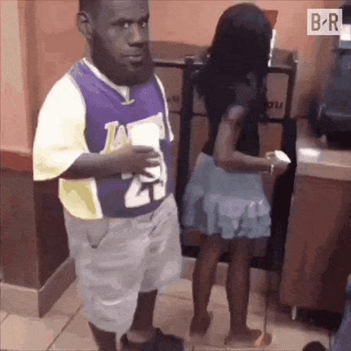 a man in a lakers jersey is standing next to a girl