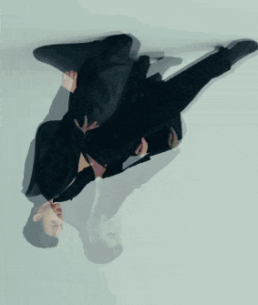 a man in a suit is upside down with his reflection in the mirror