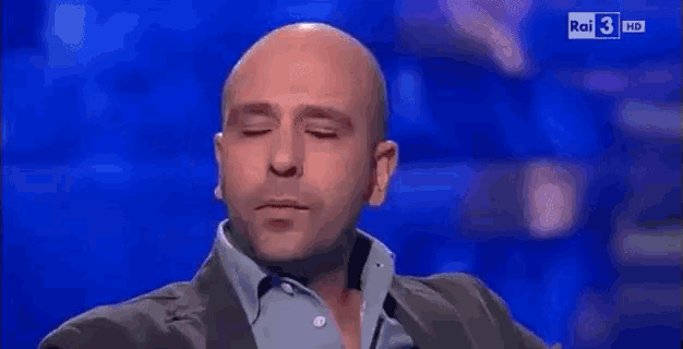 a bald man says e aspettiamo on a blue background