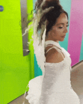 a woman in a white dress with wings is standing in front of a green door .