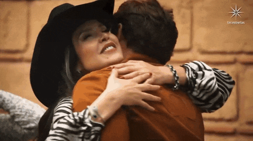 a woman in a zebra print shirt is hugging a man in a cowboy hat