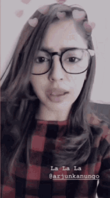 a woman wearing glasses and a plaid shirt is singing