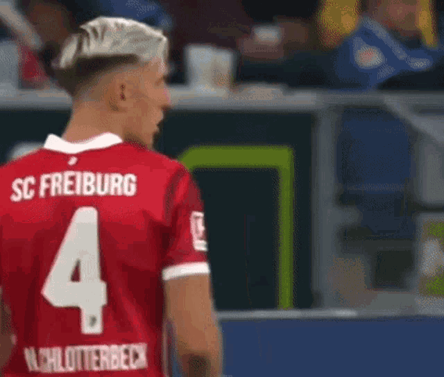 a soccer player wearing a red jersey with the number 4 on it is standing on the field .