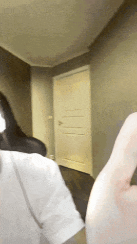 a woman in a white shirt is standing in a hallway