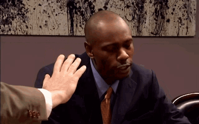 a man in a suit and tie is being touched by another man