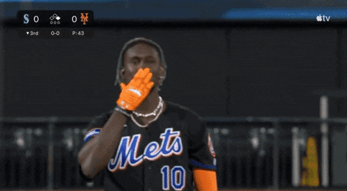 a man holds up his hand in front of a scoreboard
