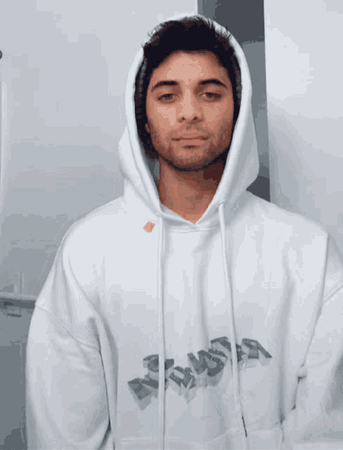 a young man wearing a white hoodie is making a gesture with his hands