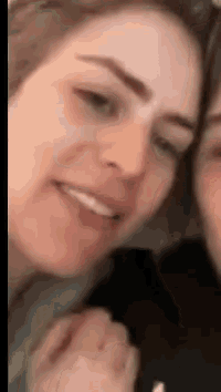 a close up of a woman 's face with a man 's hand behind her .