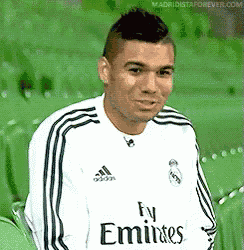 a man wearing a fly emirates jersey is sitting on a green chair .
