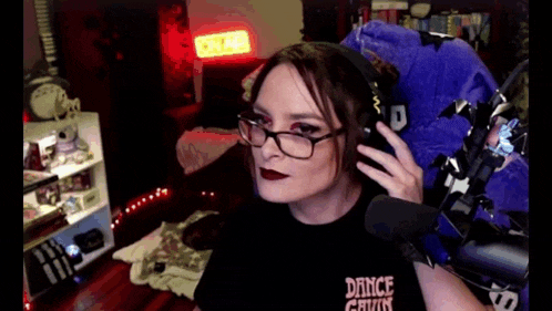 a woman wearing glasses and headphones is sitting in front of a microphone in a dark room .