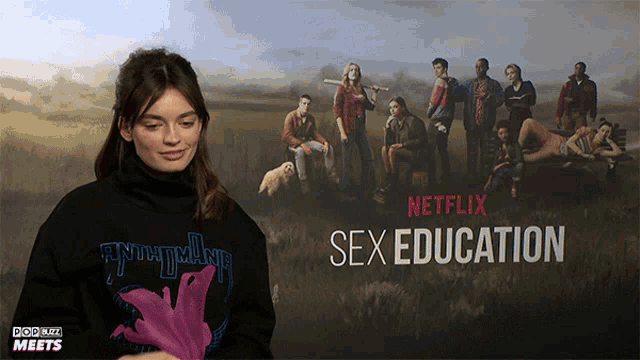 a woman standing in front of a poster for netflix sex education