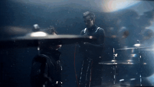a man is playing a drum set in a dark room