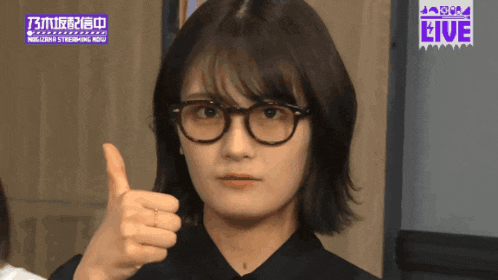 a woman wearing glasses gives a thumbs up sign