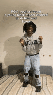 a young black rapper is standing in front of a bed wearing a hoodie that says atlanta on it