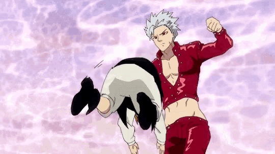 a man in a red shirt is kicking another man in the stomach .