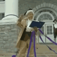 a man in a costume is holding a book in front of a building